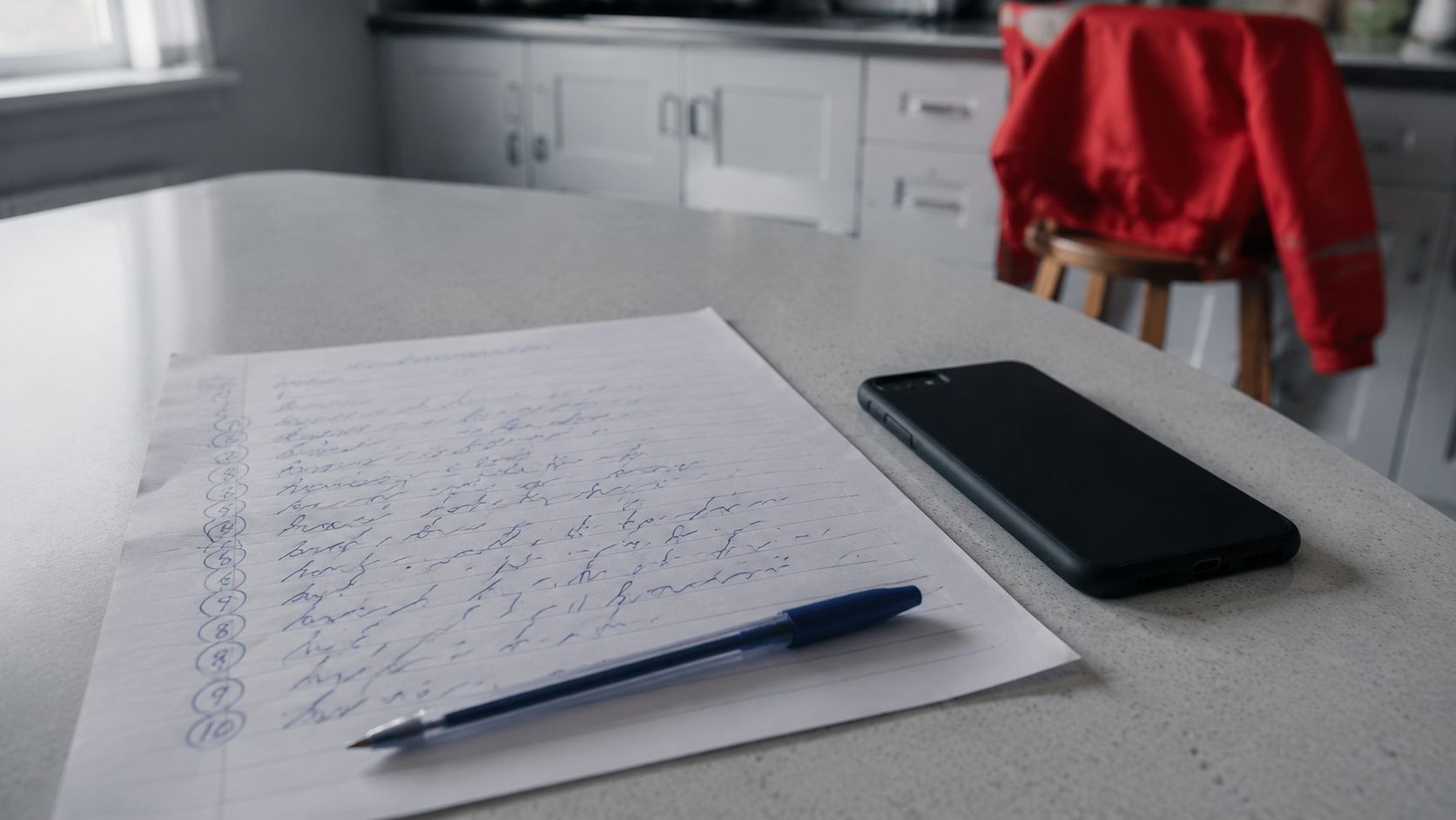 Handgeschreven lijstje met terugkerende klantvragen op een aanrecht, met een telefoon met het scherm omlaag ernaast